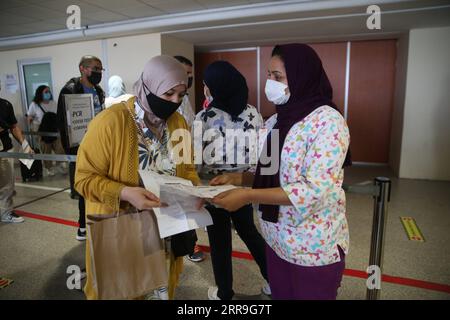 210615 -- CASABLANCA MAROCCO, 15 giugno 2021 -- un membro dello staff dell'aeroporto R, Front controlla il risultato del test PCR COVID-19 di un viaggiatore all'aeroporto internazionale Mohammed V di Casablanca, Marocco, il 15 giugno 2021. Il Marocco ha allentato le restrizioni ai confini e ha permesso ai passeggeri internazionali di entrare nel paese a partire da martedì prima della stagione turistica. MAROCCO-CASABLANCA-VIAGGIATORI-VOLI Xinhua PUBLICATIONxNOTxINxCHN Foto Stock