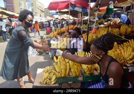 210620 -- KAMPALA, 20 giugno 2021 -- Una donna distribuisce maschere facciali a un venditore in un mercato a Kampala, Uganda, il 20 giugno 2021. Venerdì il presidente ugandese Yoweri Museveni ha annunciato una serie di misure volte a contenere la rapida diffusione del nuovo coronavirus mentre il paese sta vivendo una seconda ondata. Foto di /Xinhua UGANDA-KAMPALA-MARKET-COVID-19-MEASURES NicholasxKajoba PUBLICATIONxNOTxINxCHN Foto Stock