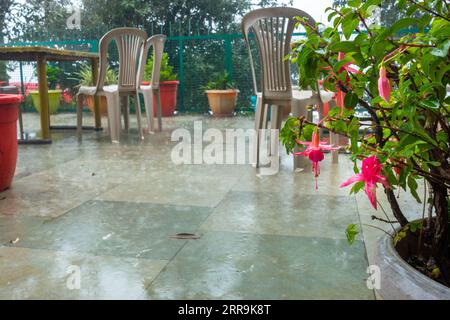 Un'immagine di un balcone giardino all'aperto con sedie vuote e un tavolo durante la stagione dei monsoni piovosi a Himachal Pradesh, India Foto Stock