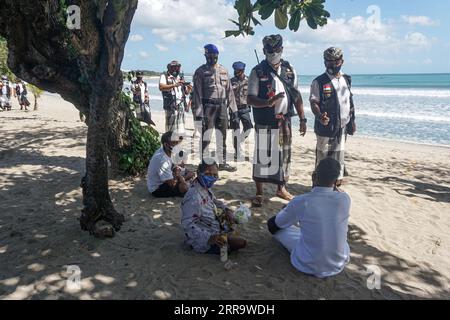 210703 -- DENPASAR, 3 luglio 2021 -- i membri del personale di sicurezza tradizionale balinese, il pecalang e gli agenti di polizia pattugliano presso il sito turistico della spiaggia di Sanur come parte delle misure locali di restrizione COVID-19 a Denpasar, Bali, Indonesia, 3 luglio 2021. L'Indonesia sabato ha registrato 27.913 nuovi casi di COVID-19 nelle ultime 24 ore, un altro record del picco giornaliero, portando il totale a 2.256.851, ha detto il Ministero della salute. Foto di /Xinhua INDONESIA-COVID-19-CASES Bisinglasi PUBLICATIONxNOTxINxCHN Foto Stock