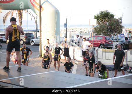 Le immagini raffigurano una lezione animata di kickboxing per bambini in Italia in occasione di un evento pubblico. Ai giovani partecipanti viene mostrato di essere attivamente impegnati in esercizi. Foto Stock