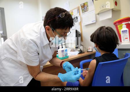 210705 -- MODIIN, 5 luglio 2021 -- un medico israeliano somministra una dose del vaccino anti COVID-19 a un ricevente in un centro di servizi sanitari a Modiin, Israele centrale, il 5 luglio 2021. L'efficacia del vaccino Pfizer contro il coronavirus è scesa a solo il 64% in Israele, ha detto il Ministero della salute del paese in una dichiarazione di lunedì. Foto di /Xinhua ISRAEL-MODIIN-COVID-19-VACCINATION GilxCohenxMagen PUBLICATIONxNOTxINxCHN Foto Stock