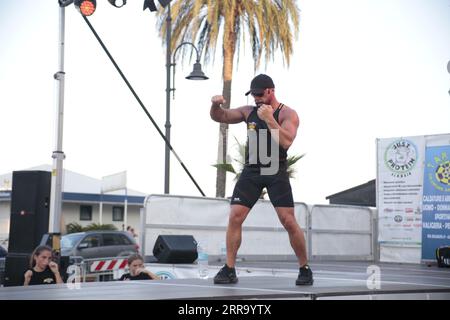 Le immagini raffigurano una lezione animata di kickboxing per bambini in Italia in occasione di un evento pubblico. Ai giovani partecipanti viene mostrato di essere attivamente impegnati in esercizi. Foto Stock