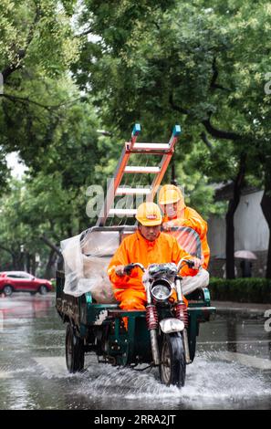 210712 -- PECHINO, 12 luglio 2021 -- i lavoratori cavalcano sotto la pioggia in una strada a Pechino, capitale della Cina, 12 luglio 2021. Secondo il dipartimento municipale per il controllo delle inondazioni, la capitale cinese Pechino è stata colpita da forti precipitazioni dalle 18:00, domenica con precipitazioni fino a 116,4 mm. Dalle 18:00 della domenica alle 9:00 del lunedì, Pechino ha registrato precipitazioni medie di 65,9 mm. Le aree urbane della città hanno riportato precipitazioni medie più alte di 79,9 mm. CINA-PECHINO-PRECIPITAZIONI PESANTI CN ChenxZhonghao PUBLICATIONxNOTxINxCHN Foto Stock