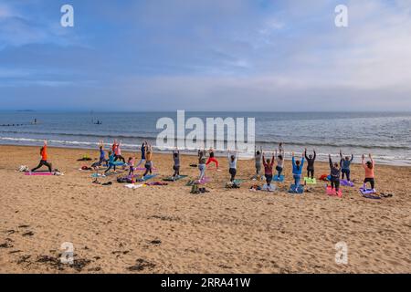 Gruppo di donne che praticano yoga con istruttore a Portobello Beach nella città di Edimburgo, Scozia, Regno Unito. Foto Stock