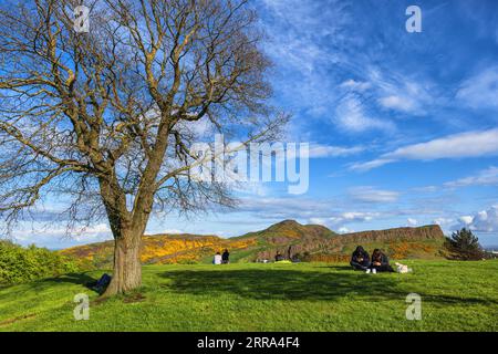 Edimburgo, Scozia, Regno Unito, le persone si rilassano sulla cima di Calton Hill in primavera con vista sull'Arthur's Seat. Foto Stock