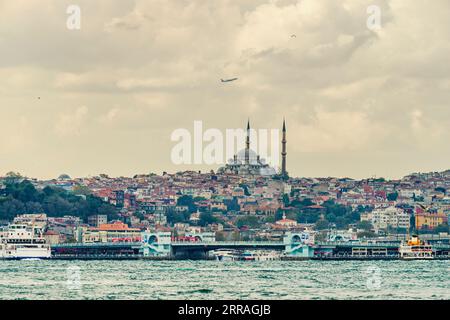 Immagine di parte del Corno d'Oro, del Ponte di Galata e di una grande moschea con due minareti e un aereo che vi sorvola Foto Stock