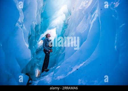 210806 -- WELLINGTON, 6 agosto 2021 -- Una guida escursionistica si trova sul fondo di un'enorme grotta di ghiaccio a Fox Glacier sulla costa occidentale dell'Isola del Sud della nuova Zelanda, 27 luglio 2020. Il ghiacciaio Fox della nuova Zelanda è da tempo un'attrazione turistica rinomata a livello internazionale. Tuttavia, Rob Jewell, CEO di Fox Glacier Guiding, è profondamente preoccupato per la cancellazione della prenotazione dopo la pausa di otto settimane della bolla di viaggio Trans-Tasman implementata alla fine di luglio, di solito la stagione d'oro per le aziende della cittadina Fox Glacier, una destinazione remota e piccola in nuova Zelanda. Funzione: Nuovo Zealan Foto Stock