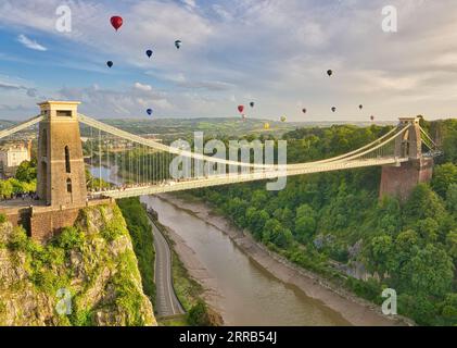 L'ascesa di massa al Bristol International Balloon Fiesta, mentre le mongolfiere colorate brillanti salgono in aria sopra il ponte sospeso di Clifton. Foto Stock