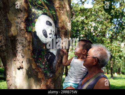 210905 -- SHANGHAI, 5 settembre 2021 -- la gente vede un buco dipinto di un albero a Zhabei Park a Shanghai, Cina orientale, 31 agosto 2021. Il Parco Zhabei ha recentemente fatto uno sforzo per migliorarne l'aspetto pulendo e abbellendo i buchi degli alberi nel parco con motivi creativi. CHINA-SHANGHAI-PARK-TREE HOLE-BEAUTIFICATION CN LIUXYING PUBLICATIONXNOTXINXCHN Foto Stock