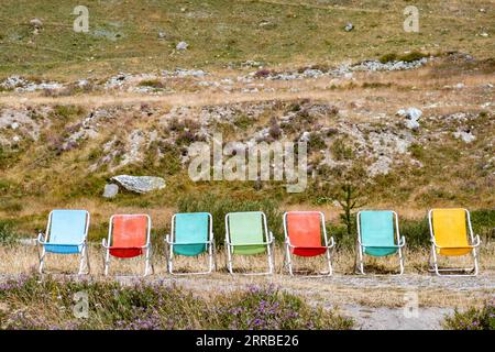 Una fila di sdraio colorate sullo sfondo di una collina erbosa Foto Stock