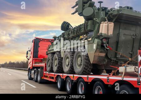 Vista posteriore del veicolo corazzato stryker con sistema di difesa aerea, autotrasportatore per rimorchi autocarri per convoglio militare su strada. Truppe STATUNITENSI in movimento Foto Stock