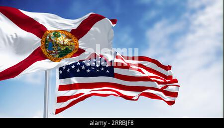 Bandiere della Florida e degli Stati Uniti che sventolano al vento in una giornata limpida. La Florida è uno stato nel sud-est degli Stati Uniti. Stato federato DEGLI STATI UNITI. illustrazione 3d re Foto Stock