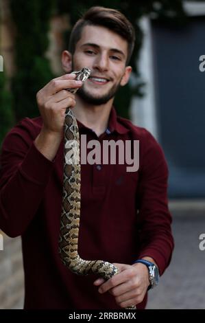 211005 -- RAMALLAH, 5 ottobre 2021 -- il palestinese Mohammed Nassri tiene un serpente nella sua casa, nel villaggio di Bir Nabala a sud della città di Ramallah, 29 settembre 2021. ANDARE CON: Caratteristica: Giovane palestinese fa vivere da serpenti giganti e pericolosi foto di /Xinhua MIDEAST-RAMALLAH-SNAKES AymanxNobani PUBLICATIONxNOTxINxCHN Foto Stock