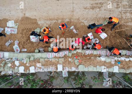 211010 -- HEJIN, 10 ottobre 2021 -- foto aerea mostra i soccorritori che fortificano la diga temporanea contro l'inondazione nel villaggio di Lianbo nella città di Hejin, nella provincia dello Shanxi della Cina settentrionale, 10 ottobre 2021. Più di 120.000 persone sono state temporaneamente evacuate dopo continue inondazioni innescate nella provincia dello Shanxi della Cina settentrionale, hanno detto domenica le autorità. Le inondazioni hanno sconvolto la vita di 1,76 milioni di residenti provenienti da 76 contee, città e distretti, secondo il dipartimento provinciale di gestione delle emergenze. Circa 190.000 ettari di colture furono danneggiati e più di 17.000 case crollarono, il de Foto Stock