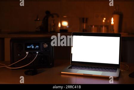 Stazione di ricarica per laptop e lampada da scrivania quando non c'è luce durante il blackout. Batteria del gruppo di alimentazione del generatore in assenza di elettricità. a casa Foto Stock