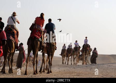 211022 -- CAIRO, 22 ottobre 2021 -- i turisti cavalcano i cammelli per vedere le piramidi di Giza a Giza, Egitto, il 21 ottobre 2021. L'Egitto è entrato nella stagione turistica di picco, poiché il tempo sta diventando più fresco, e i voli internazionali verso il paese sospesi a causa della COVID-19 stanno gradualmente riprendendo. Il punto panoramico delle piramidi di Giza è visitato da sempre più turisti. EGITTO-PIRAMIDI di GIZA-TURISMO-RECUPERO WangxDongzhen PUBLICATIONxNOTxINxCHN Foto Stock