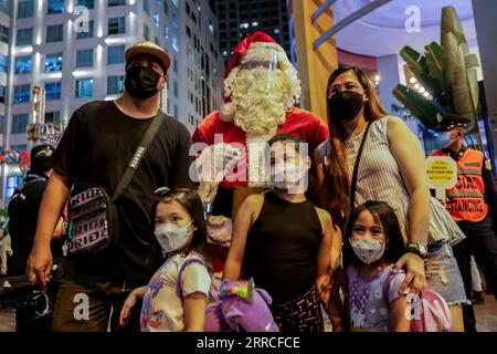 211104 -- QUEZON CITY, 4 novembre 2021 -- Un uomo vestito da Babbo Natale con una maschera protettiva posa per una foto con una famiglia durante il lancio di una mostra natalizia in un centro commerciale a Quezon City, nelle Filippine, il 4 novembre 2021. Il livello di allerta nella regione della capitale filippina sarà ulteriormente ridotto a 2 su una scala di 5 a partire da venerdì, con il rallentamento delle infezioni da COVID-19 e l'aumento del tasso di vaccinazione, ha affermato giovedì il portavoce presidenziale filippino Harry Roque. FILIPPINE-QUEZON CITY-COVID-19-RESTRICTIONS-EASE ROUELLEXUMALI PUBLICATIONXNOTXINXCHN Foto Stock