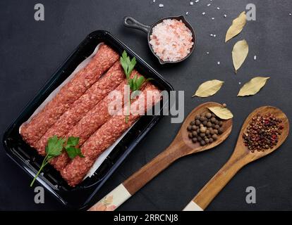 Salsicce crude al kebab di lula su tavola e spezie, vista dall'alto Foto Stock