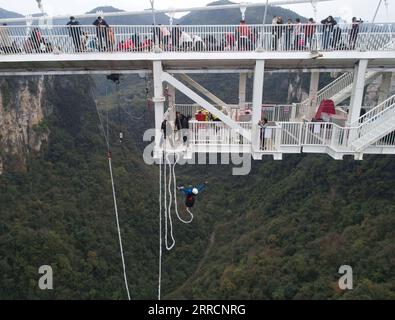 211112 -- ZHANGJIAJIE, 12 novembre 2021 -- foto aerea scattata il 12 novembre 2021 mostra un turista che fa bungee jumping dal ponte con fondo in vetro del Grand Canyon di Zhangjiajie, nella provincia centrale di Hunan della Cina. Il ponte lungo 430 metri e largo sei metri, che collega due scogliere ripide a 300 metri dal suolo, è pavimentato con 99 pannelli di vetro trasparente a tre strati. CHINA-HUNAN-ZHANGJIAJIE-GLASS BRIDGE CN ZHAOXZHONGZHI PUBLICATIONXNOTXINXCHN Foto Stock