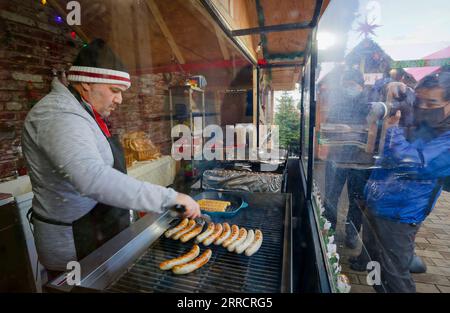 211116 -- VANCOUVER, 16 novembre 2021 -- Un venditore di negozi prepara salsicce tedesche per i clienti al Vancouver Christmas Market al Jack Poole Plaza di Vancouver, British Columbia, 15 novembre 2021. Rinviato nel 2020 a causa della pandemia di COVID-19, il mercato di Natale di Vancouver è tornato per il suo undicesimo anno. Il mercato presenta circa 80 capanne ripiene di cibo, prelibatezze, artigianato tradizionale e diverse attività festive per la gente del posto e i visitatori. Foto di /Xinhua CANADA-VANCOUVER-CHRISTMAS MARKET LiangxSen PUBLICATIONxNOTxINxCHN Foto Stock