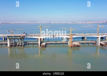 News Bilder des Tages 211130 -- QUANZHOU, 30 novembre 2021 -- foto aerea scattata il 30 novembre 2021 mostra il ponte di Quanzhou Bay della ferrovia ad alta velocità Fuzhou-Xiamen nella provincia del Fujian della Cina sud-orientale. La struttura principale del ponte sul mare della baia di Quanzhou, parte della ferrovia ad alta velocità Fuzhou-Xiamen di 277 km, è stata completata martedì. Il ponte ha una lunghezza totale di 20,29 km, con un ponte marittimo di 8,96 km. Con una velocità progettata di 350 km all'ora, si prevede che la ferrovia ad alta velocità riduca il tempo di viaggio dalla capitale della provincia Fuzhou all'attrazione turistica Xiam Foto Stock