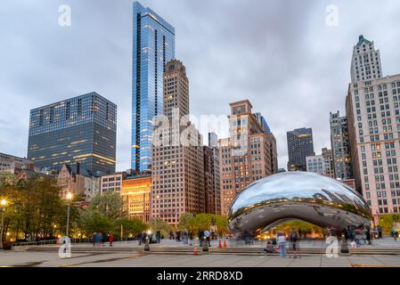 Chicago, Illinois - 29 aprile 2023: Persone che camminano e scattano foto del Chicago Cloud Gate nel Millennium Park al crepuscolo Foto Stock