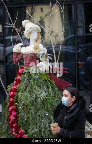 211211 -- VANCOUVER, 11 dicembre 2021 -- Una donna cammina davanti a un'installazione floreale durante la mostra floreale Fleurs de Villes Noel a Vancouver, British Columbia, Canada, l'11 dicembre 2021. La mostra floreale all'aperto Fleurs de Villes Noel è presentata a Vancouver dal 10 al 19 dicembre, con oltre 40 installazioni pop-up create da fioristi locali. Foto di /Xinhua CANADA-VANCOUVER-INSTALLAZIONI FLOREALI LiangxSen PUBLICATIONxNOTxINxCHN Foto Stock