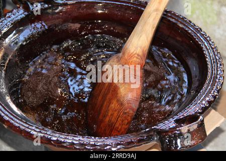 Preparazione della talpa rossa, un tipico piatto messicano in una pentola di argilla con un gigantesco cucchiaio di legno sul fuoco di una stufa con tutti gli ingredienti integrati Foto Stock