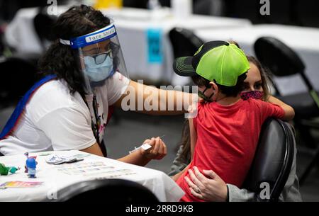 211212 -- TORONTO, 12 dicembre 2021 -- Un vaccinatore che indossa una maschera facciale e uno scudo facciale si prepara a somministrare il vaccino COVID-19 a un bambino in un sito di vaccinazione a Toronto, Canada, il 12 dicembre 2021. La città di Toronto domenica ha ospitato un evento di vaccinazione di massa a tema supereroe come Toronto Kids Vaccine Day per vaccinare fino a 2.000 bambini di età compresa tra i cinque e gli 11 anni contro la COVID-19. Foto di /Xinhua CANADA-TORONTO-KIDS VACCINO DAY ZouxZheng PUBLICATIONxNOTxINxCHN Foto Stock