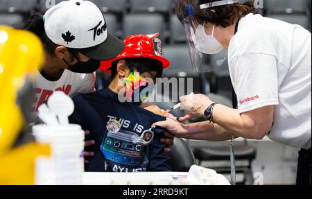 211212 -- TORONTO, 12 dicembre 2021 -- Un vaccinatore che indossa una maschera facciale e uno scudo facciale somministra un bambino il vaccino COVID-19 in un sito di vaccinazione a Toronto, Canada, il 12 dicembre 2021. La città di Toronto domenica ha ospitato un evento di vaccinazione di massa a tema supereroe come Toronto Kids Vaccine Day per vaccinare fino a 2.000 bambini di età compresa tra i cinque e gli 11 anni contro la COVID-19. Foto di /Xinhua CANADA-TORONTO-KIDS VACCINO DAY ZouxZheng PUBLICATIONxNOTxINxCHN Foto Stock