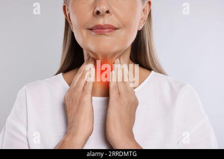 Sistema endocrino. Donna che fa l'autoesame della tiroide su sfondo grigio chiaro, primo piano Foto Stock