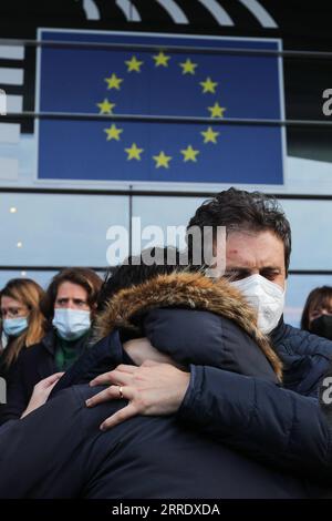 220111 -- BRUXELLES, 11 gennaio 2022 -- le persone si abbracciano dopo aver osservato un momento di silenzio in memoria del presidente del Parlamento europeo David Sassoli, davanti al Parlamento europeo a Bruxelles, in Belgio, 11 gennaio 2022. Il Presidente del Parlamento europeo David Sassoli è morto all'età di 65 anni in un ospedale in Italia all'inizio di martedì, ha detto il suo portavoce. Sassoli, nato il 30 maggio 1956, a Firenze, Italia, era stato ricoverato in ospedale per più di due settimane a causa di una grave complicazione relativa alla disfunzione del sistema immunitario. Sassoli fu eletto al Parlamento europeo nel 2009. E' diventato presidente di Foto Stock