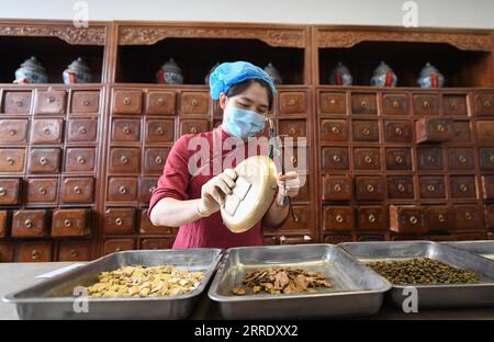 220112 -- TIANJIN, 12 gennaio 2022 -- Un farmacista pesa ingredienti per produrre la medicina tradizionale cinese TCM decoctions presso il First Teaching Hospital of Tianjin University of Traditional Chinese Medicine in North China S Tianjin, 12 gennaio 2022. La MTC è stata ampiamente applicata nella prevenzione e nel controllo della COVID-19 a Tianjin, migliorando la capacità immunitaria degli individui in quarantena medica. CHINA-TIANJIN-COVID-19-TCM CN SunxFanyue PUBLICATIONxNOTxINxCHN Foto Stock