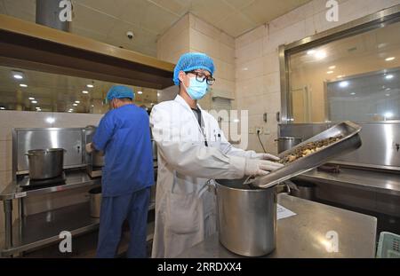 220112 -- TIANJIN, 12 gennaio 2022 -- i farmacisti preparano ingredienti per produrre la medicina tradizionale cinese i decotti TCM presso il First Teaching Hospital of Tianjin University of Traditional Chinese Medicine in North China S Tianjin, 12 gennaio 2022. La MTC è stata ampiamente applicata nella prevenzione e nel controllo della COVID-19 a Tianjin, migliorando la capacità immunitaria degli individui in quarantena medica. CHINA-TIANJIN-COVID-19-TCM CN ZhaoxZishuo PUBLICATIONxNOTxINxCHN Foto Stock