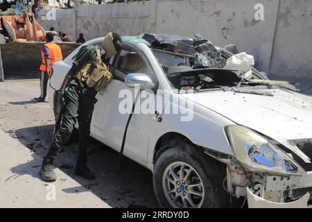 220112 -- MOGADISCIO, 12 gennaio 2022 -- Un membro della sicurezza controlla un'auto sul luogo di un attentato suicida a Mogadiscio, Somalia, il 12 gennaio 2022. Almeno dieci persone, tra cui cinque soldati, sono state uccise e altre nove ferite in un attentato suicida avvenuto mercoledì nella capitale somala, Mogadiscio, hanno detto i funzionari. Foto di /Xinhua SOMALIA-MOGADISCIO-ATTENTATO SUICIDA HassanxBashi PUBLICATIONxNOTxINxCHN Foto Stock