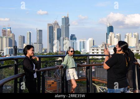 220123 -- GIACARTA, 23 gennaio 2022 -- la gente posa per delle foto sullo Skywalk del Senayan Park a Giacarta, Indonesia, 23 gennaio 2022. Il 18 gennaio i legislatori indonesiani hanno approvato una legge sul trasferimento della capitale della nazione sull'isola di Kalimantan, che il paese confina con la Malesia e il Brunei, dall'isola più popolata di Giava. Nusantara, che la nuova capitale è chiamata, sarà costruita in due distretti del Kalimantan orientale: Penajam Paser Utara e Kutai Kartanegara. Si prevede che occuperà circa 256.000 ettari di terreno. Nusantara servirà come centro del governo, mentre Giacarta W Foto Stock