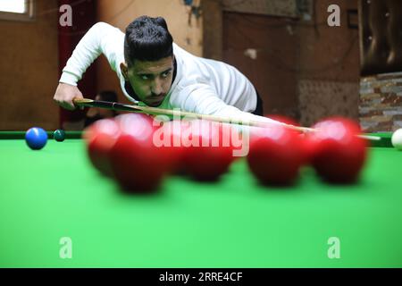 220126 -- GAZA, 26 gennaio 2022 -- il giovane palestinese Ahmed Nasr gioca a snooker all'interno di un club sportivo locale nella città meridionale di Rafah, nella Striscia di Gaza, il 26 gennaio 2022. Nasr, 22 anni, ha imparato a giocare a snooker e a biliardo da suo padre, poi ha imparato le regole del gioco attraverso i video di YouTube. Recentemente ha vinto il primo posto nel campionato di snooker della Striscia di Gaza, che lo ha qualificato per il campionato di classifica a livello della squadra palestinese. Foto di Khaled Omar/Xinhua SPMIDEAST-GAZA-RAFAH-SNOOKER EmadxDrimly PUBLICATIONxNOTxINxCHN Foto Stock