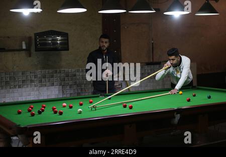 220126 -- GAZA, 26 gennaio 2022 -- il giovane palestinese Ahmed Nasr R gioca a snooker all'interno di un club sportivo locale nella città meridionale di Rafah, nella Striscia di Gaza, il 26 gennaio 2022. Nasr, 22 anni, ha imparato a giocare a snooker e a biliardo da suo padre, poi ha imparato le regole del gioco attraverso i video di YouTube. Recentemente ha vinto il primo posto nel campionato di snooker della Striscia di Gaza, che lo ha qualificato per il campionato di classifica a livello della squadra palestinese. Foto di Khaled Omar/Xinhua SPMIDEAST-GAZA-RAFAH-SNOOKER EmadxDrimly PUBLICATIONxNOTxINxCHN Foto Stock