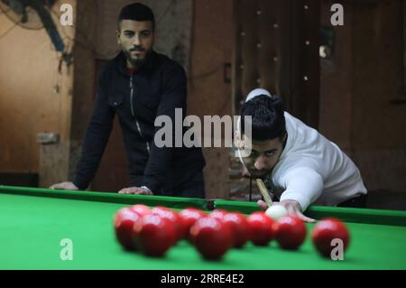 220126 -- GAZA, 26 gennaio 2022 -- il giovane palestinese Ahmed Nasr R gioca a snooker all'interno di un club sportivo locale nella città meridionale di Rafah, nella Striscia di Gaza, il 26 gennaio 2022. Nasr, 22 anni, ha imparato a giocare a snooker e a biliardo da suo padre, poi ha imparato le regole del gioco attraverso i video di YouTube. Recentemente ha vinto il primo posto nel campionato di snooker della Striscia di Gaza, che lo ha qualificato per il campionato di classifica a livello della squadra palestinese. Foto di Khaled Omar/Xinhua SPMIDEAST-GAZA-RAFAH-SNOOKER EmadxDrimly PUBLICATIONxNOTxINxCHN Foto Stock