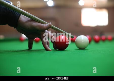 220126 -- GAZA, 26 gennaio 2022 -- il giovane palestinese Ahmed Nasr gioca a snooker all'interno di un club sportivo locale nella città meridionale di Rafah, nella Striscia di Gaza, il 26 gennaio 2022. Nasr, 22 anni, ha imparato a giocare a snooker e a biliardo da suo padre, poi ha imparato le regole del gioco attraverso i video di YouTube. Recentemente ha vinto il primo posto nel campionato di snooker della Striscia di Gaza, che lo ha qualificato per il campionato di classifica a livello della squadra palestinese. Foto di Khaled Omar/Xinhua SPMIDEAST-GAZA-RAFAH-SNOOKER EmadxDrimly PUBLICATIONxNOTxINxCHN Foto Stock