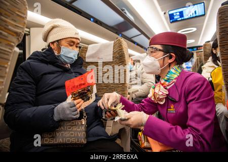 220202 -- CHONGQING, 2 febbraio 2022 -- Lin Mengfan dà il cambio a un passante anziano che ha acquistato degli snack a bordo di un treno proiettile Fuxing viaggiando sulla ferrovia Chendu-Chongqing nel sud-ovest della Cina, 27 gennaio 2022. Nata nel 2000, Lin Mengfan è una hostess principiante per un treno proiettile Fuxing sulla ferrovia Chendu-Chongqing. Nel frattempo, Lin è al servizio della corsa di viaggio del Festival di Primavera per la prima volta nella sua carriera. Se c'è un passeggero che ha bisogno di aiuto a bordo, Lin ha preparato con sé una versatile borsa portautensili. Nella custodia sono presenti adesivi colorati per i passegger che segnano i bagagli, i cartoni animati Foto Stock