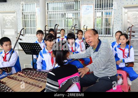 220217 -- HAIKOU, 17 febbraio 2022 -- Huang Zihe, erede di Hainan Bayin, insegna agli studenti le tecniche di gioco di Hainan Bayin in una scuola nel distretto di Meilan di Haikou, provincia di Hainan, Cina meridionale, 23 novembre 2018. Hainan Bayin, o Hainan otto Tunes, si riferisce letteralmente agli otto tipi di strumenti musicali fatti di materiali coltivati a Hainan, come conchiglie di cocco e legno di palissandro cinese. Si riferisce anche allo stile musicale Bayin creato con lo strumento. DA SEGUIRE in tutta la Cina: In Cina, Hainan, un artista di 86 anni dona un tocco moderno alla musica tradizionale CHINA-HAINAN-TRADITION Foto Stock