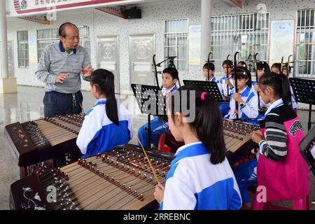 220217 -- HAIKOU, 17 febbraio 2022 -- Huang Zihe, erede di Hainan Bayin, insegna agli studenti le tecniche di gioco di Hainan Bayin in una scuola nel distretto di Meilan di Haikou, provincia di Hainan, Cina meridionale, 23 novembre 2018. Hainan Bayin, o Hainan otto Tunes, si riferisce letteralmente agli otto tipi di strumenti musicali fatti di materiali coltivati a Hainan, come conchiglie di cocco e legno di palissandro cinese. Si riferisce anche allo stile musicale Bayin creato con lo strumento. DA SEGUIRE in tutta la Cina: In Cina, Hainan, un artista di 86 anni dona un tocco moderno alla musica tradizionale CHINA-HAINAN-TRADITION Foto Stock