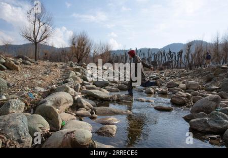 220218 -- SRINAGAR, 18 febbraio 2022 -- Un ragazzo attraversa un ruscello parzialmente secco in un villaggio nel distretto di Anantnag, circa 94 km a sud della città di Srinagar, la capitale estiva del Kashmir controllato dagli indiani, 18 febbraio 2022. Una dolina verticale che si è sviluppata nel mezzo di un letto di fiume ha divorato un flusso d'acqua dolce nel Kashmir controllato dagli indiani, hanno detto i funzionari giovedì. La dolina ha prosciugato tutta la corrente d'acqua in essa e ha lasciato asciutta la parte a valle, uccidendo in gran numero i pesci di trota. Ha anche causato danni incommensurabili alla vita acquatica. KASHMIR-SRINAGAR-VERTICAL SI Foto Stock