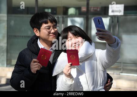 220222 -- PECHINO, 22 febbraio 2022 -- una coppia in possesso dei loro certificati di matrimonio posa una foto all'esterno di un registro matrimoniale del distretto di Haidian a Pechino, capitale della Cina, 22 febbraio 2022. 22 febbraio del 2022, una data con numeri di 2 che risuonano approssimativamente la pronuncia dell'amore nel cinese parlato, è preferibile dalle coppie per registrare il matrimonio per i buoni auguri. CHINA-20220222-COPPIA-AMORE CN RenxChao PUBLICATIONxNOTxINxCHN Foto Stock