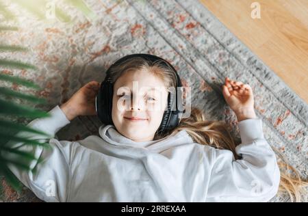 Simpatica bambina che ascolta la musica in cuffia a casa. Foto Stock