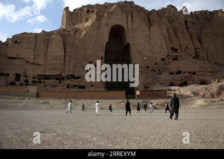 220319 -- BAMIYAN, 19 marzo 2022 -- foto scattata il 18 marzo 2022 mostra persone che giocano a calcio vicino al sito della statua del Buddha di Bamiyan nella provincia di Bamiyan, Afghanistan centrale. Foto di /Xinhua AFGHANISTAN-BAMIYAN-BUDDHA STATUA SaifurahmanxSafi PUBLICATIONxNOTxINxCHN Foto Stock