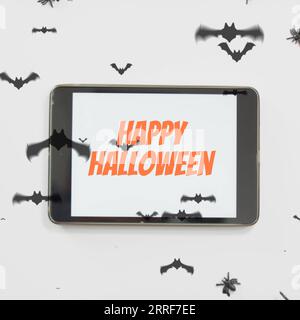 Composizione di testo Happy halloween su tablet e pipistrelli halloween su sfondo bianco Foto Stock