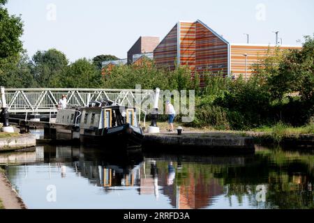 Un narrowboat che parte dal basso di Cape Lock, Grand Union Canal, Warwick, Regno Unito Foto Stock